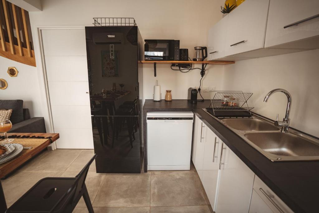 a kitchen with a sink and a black refrigerator at KozyKaz, notre villa cocooning avec piscine in Saint-Pierre