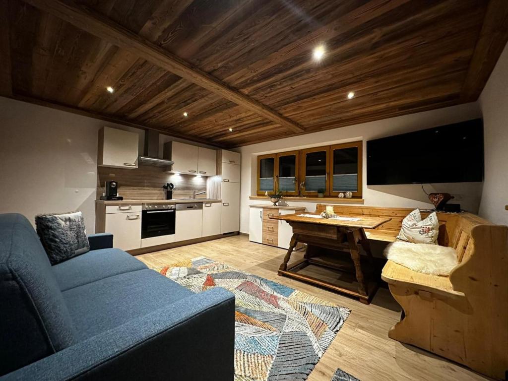 a living room with a blue couch and a kitchen at Ferienwohnung Bergzua in Stummerberg