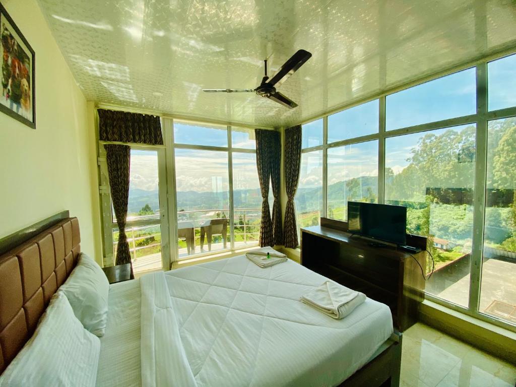 a bedroom with a bed and a large window at Tulips Village Resorts in Ooty