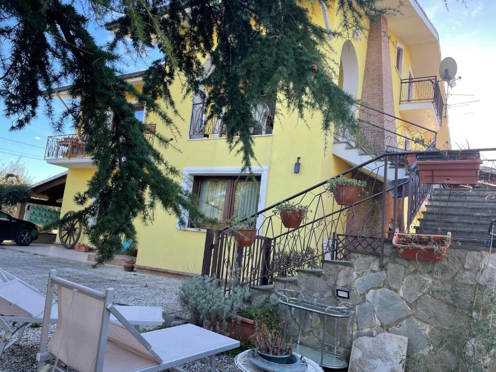una casa amarilla con escaleras y sillas delante en casa vacanze relax, en Vacri