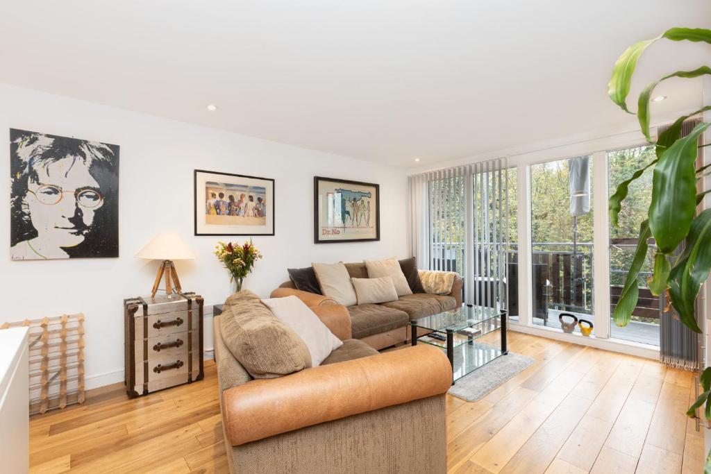 ein Wohnzimmer mit einem Sofa und einem Tisch in der Unterkunft Immaculate 2BR Flat, Greenwich, 2 min Maze Hill St in London