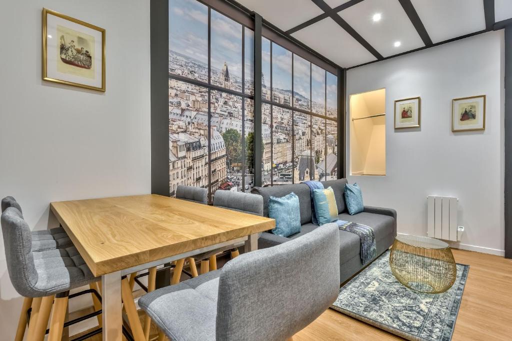 - un salon avec une table, des chaises et une grande fenêtre dans l'établissement 114 - Urban Saint Denis Couture, à Paris