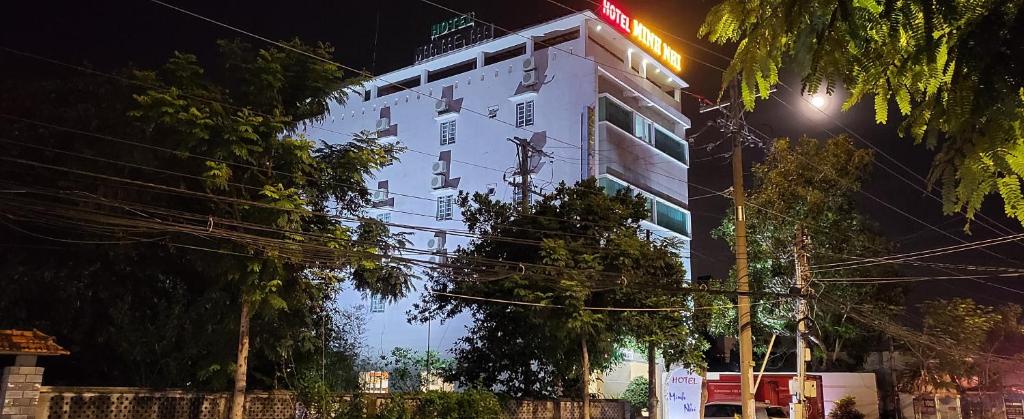 een wit gebouw met 's nachts een bord bij Minh Nhi Hotel in La Gi