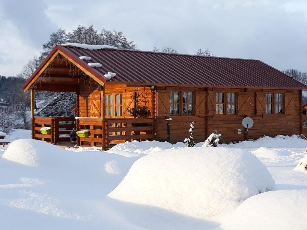 una cabaña de madera con una pila de nieve delante de ella en chalets les 5 loups, en Gerbépal
