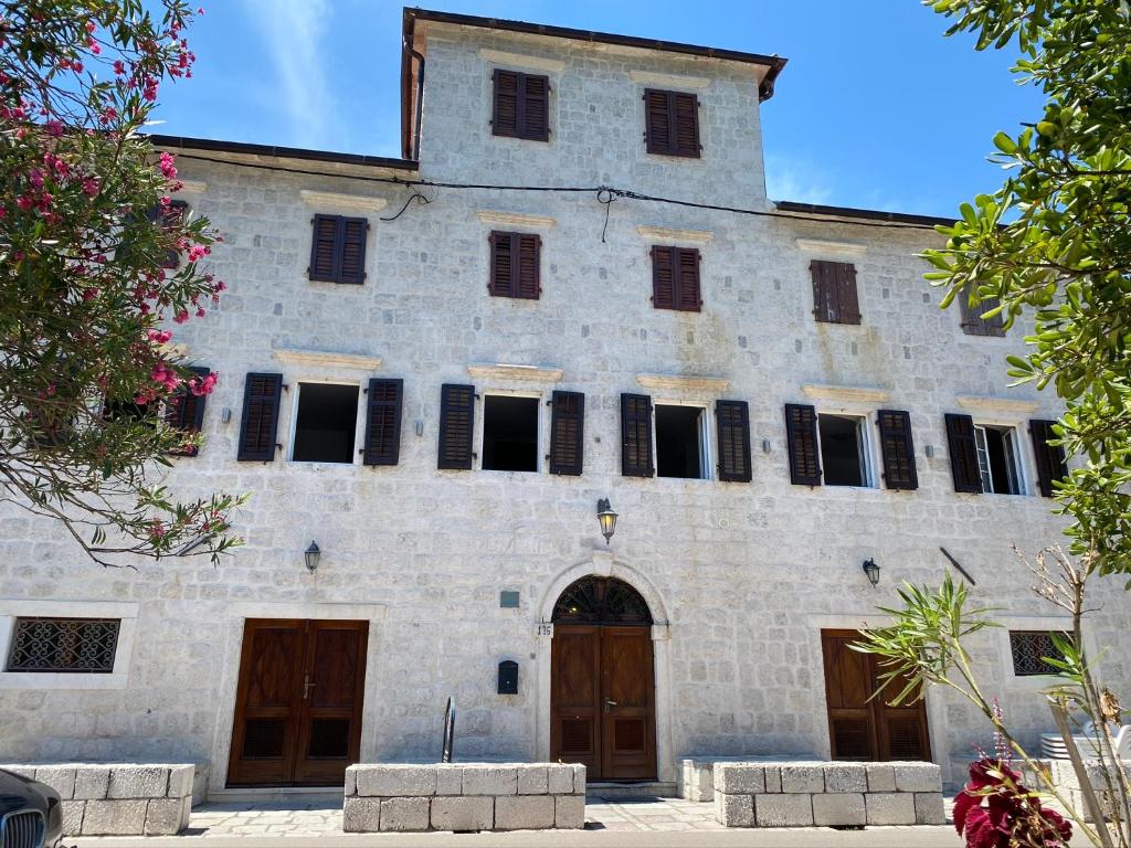 - un vieux bâtiment en pierre avec des portes et des fenêtres marron dans l'établissement VillaOldMariner, à Prčanj