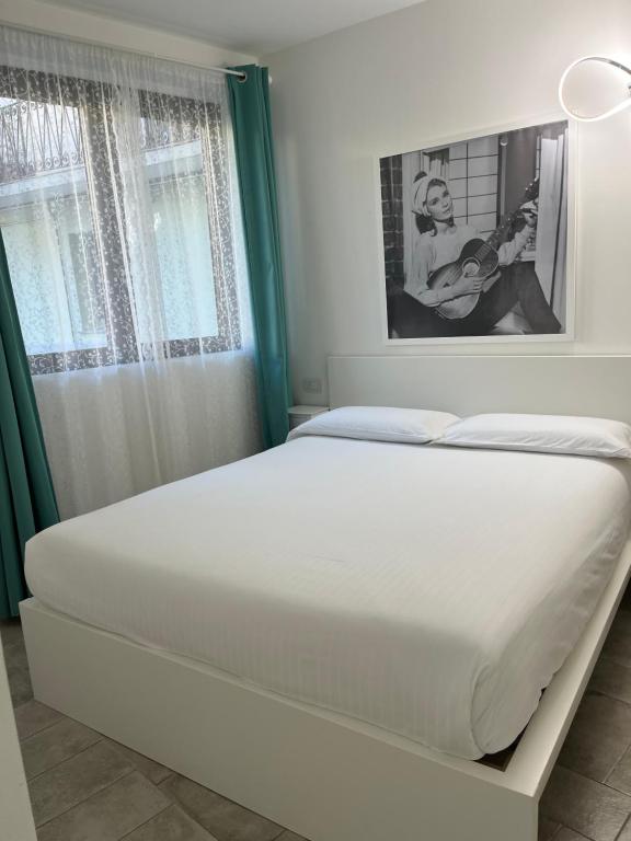 un letto bianco in una stanza con finestra di Seriana a Orio al Serio
