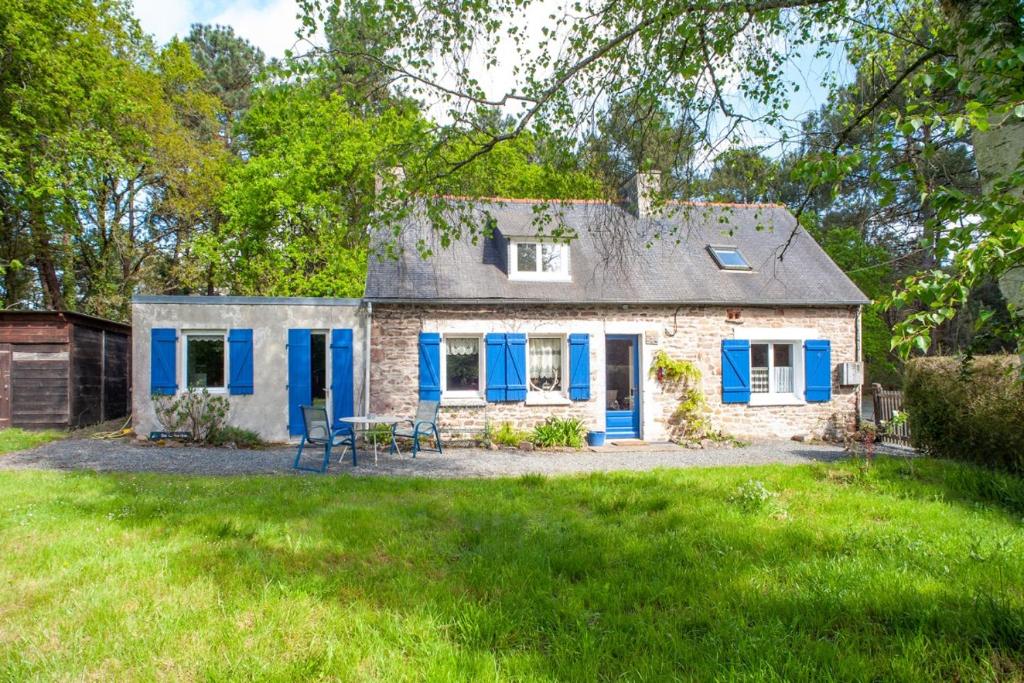 una vieja casa de ladrillo con puertas azules y un patio en Maison forestière en Plouézec
