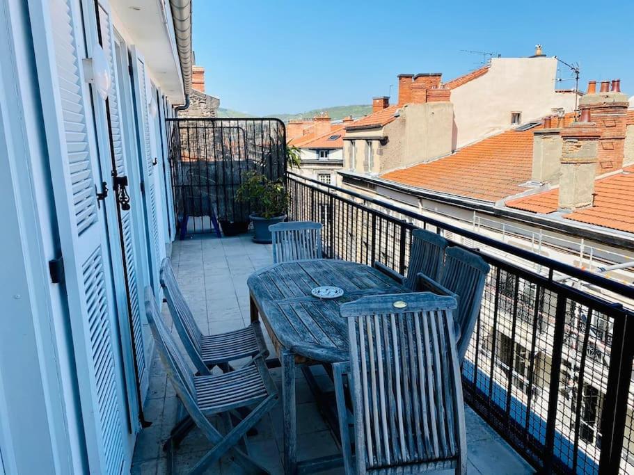 une table en bois et deux chaises sur un balcon dans l'établissement Hypercentre Clermont-FD terrasse + parking, à Clermont-Ferrand