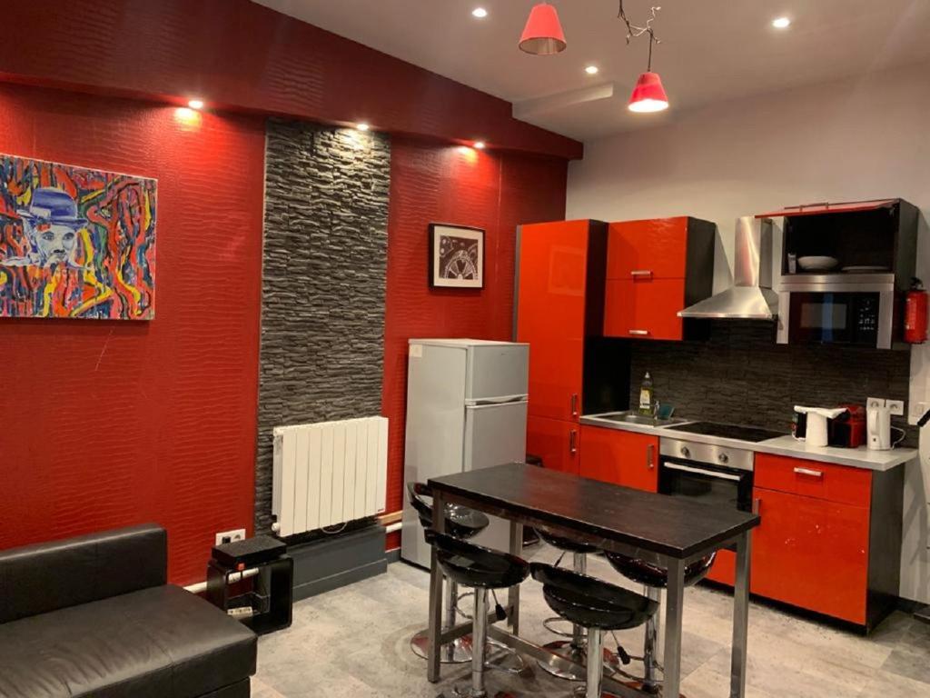 eine Küche mit roten Wänden, einem Tisch und einem Kühlschrank in der Unterkunft 21 Atelier Chaplin Montorgueil in Paris