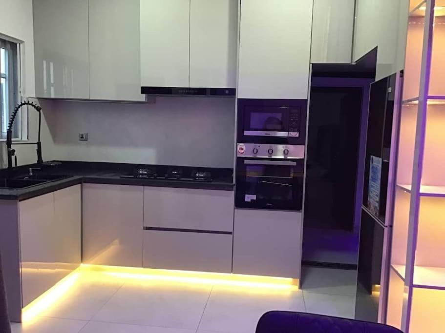 una cucina con armadietti bianchi ed elettrodomestici con luci di Brandison Apartments a Rumodome