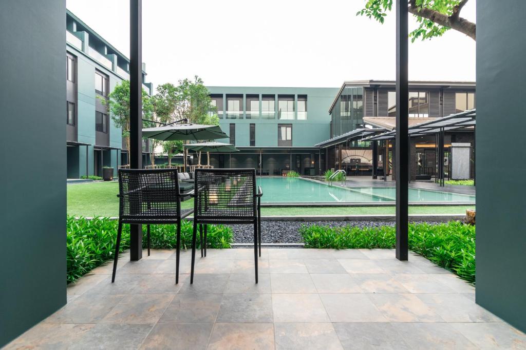 A shaded patio with two chairs looking across the hotel pool.