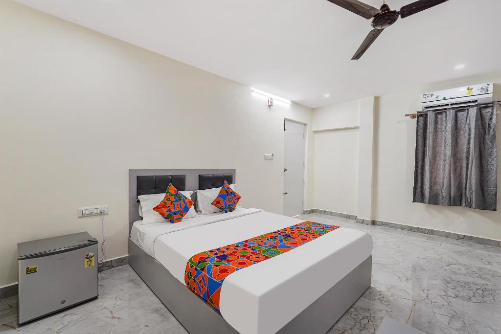 a white bedroom with a large bed with colorful pillows at FabHotel Ivory Pearl in Bangalore