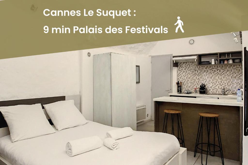 une chambre avec un lit avec des draps blancs et une cuisine dans l'établissement Le Panisse - Studio - 9 min Palais - Cannes, à Cannes