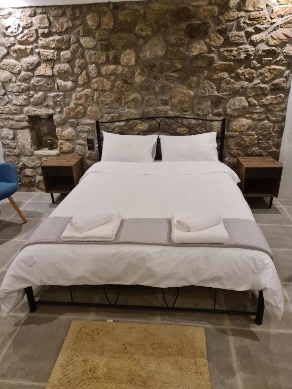 duże łóżko w pokoju z kamienną ścianą w obiekcie Villas Kertezi w Kalawricie