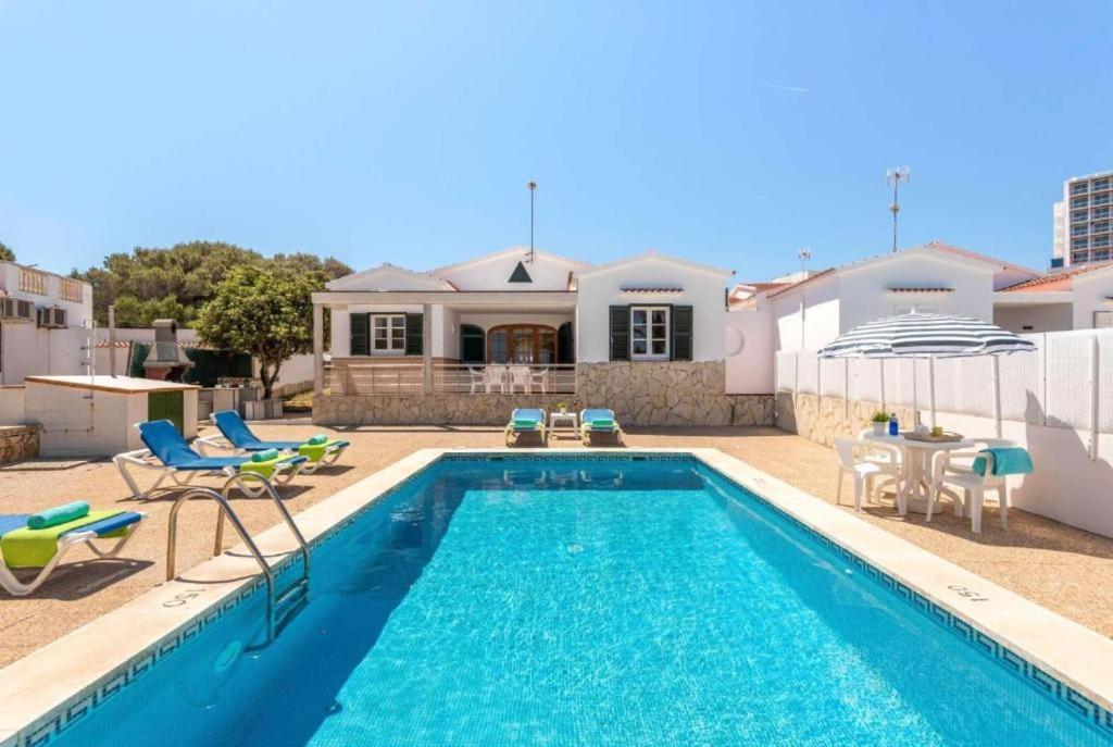 una piscina con sillas y una casa en Villa Mar Azul en Arenal d'en Castell