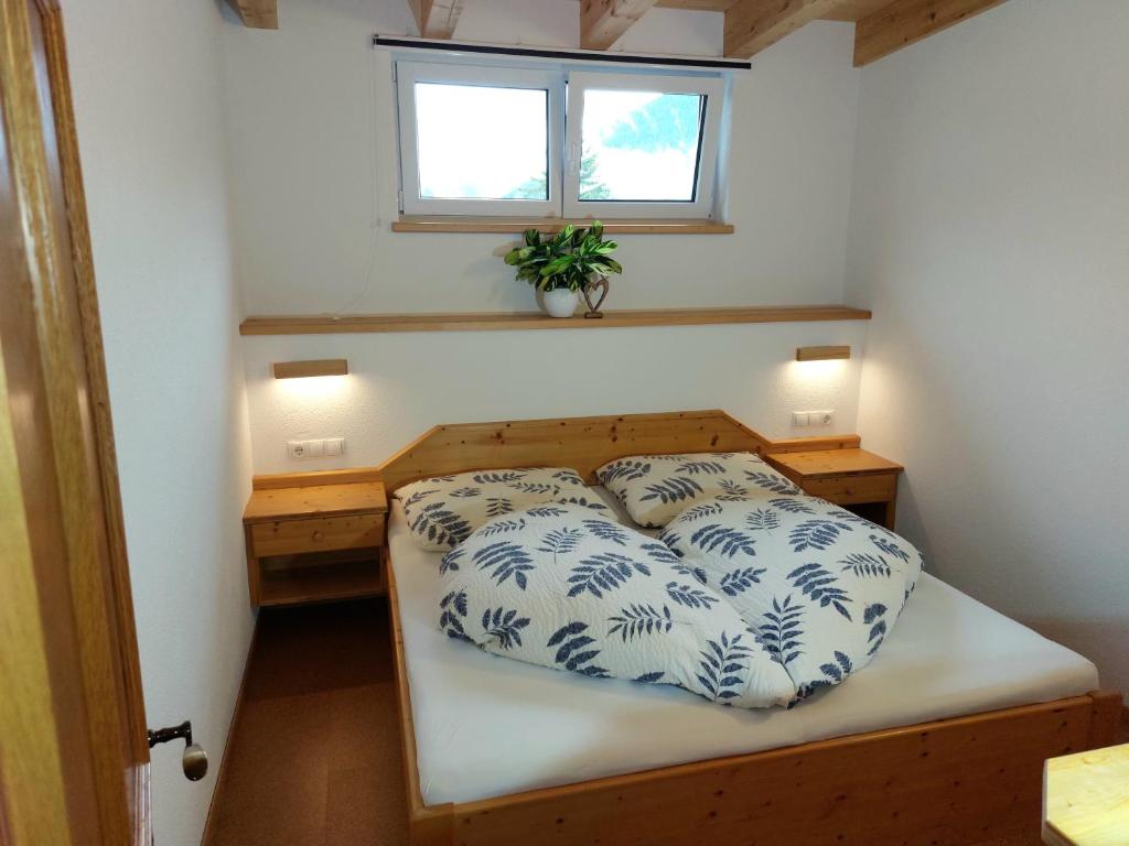 Dormitorio pequeño con cama con almohadas azules y blancas en Apartments Amelie Kaunerberg -1-, en Kaunerberg