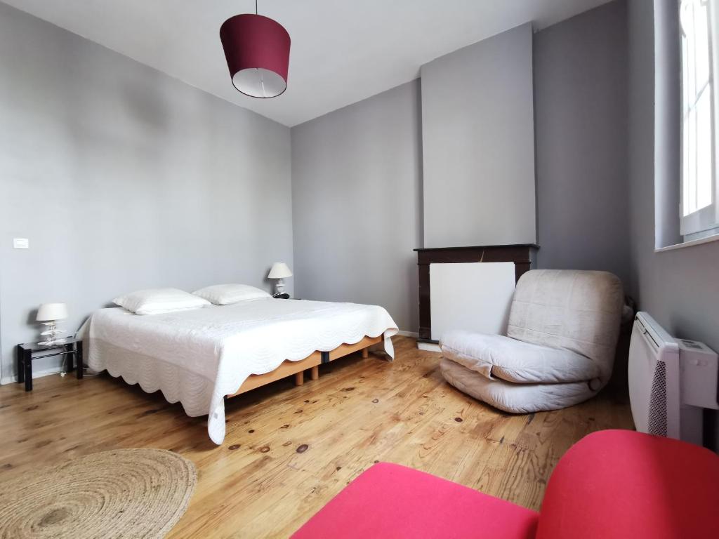 a white bedroom with a bed and a chair at Logement vue Garonne in Bordeaux