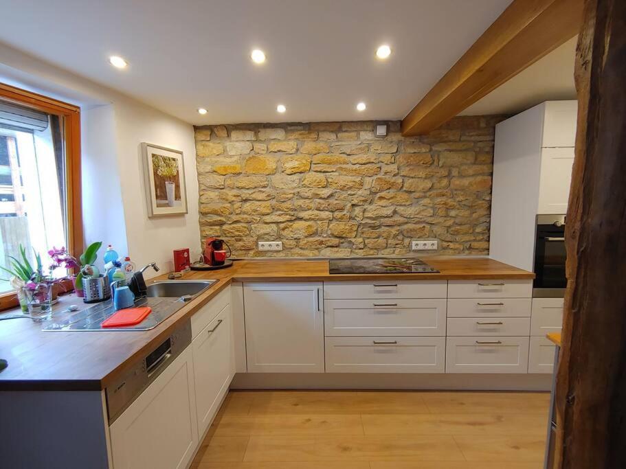 a kitchen with white cabinets and a stone wall at Sabrina's Sandsteinhaus in Flonheim