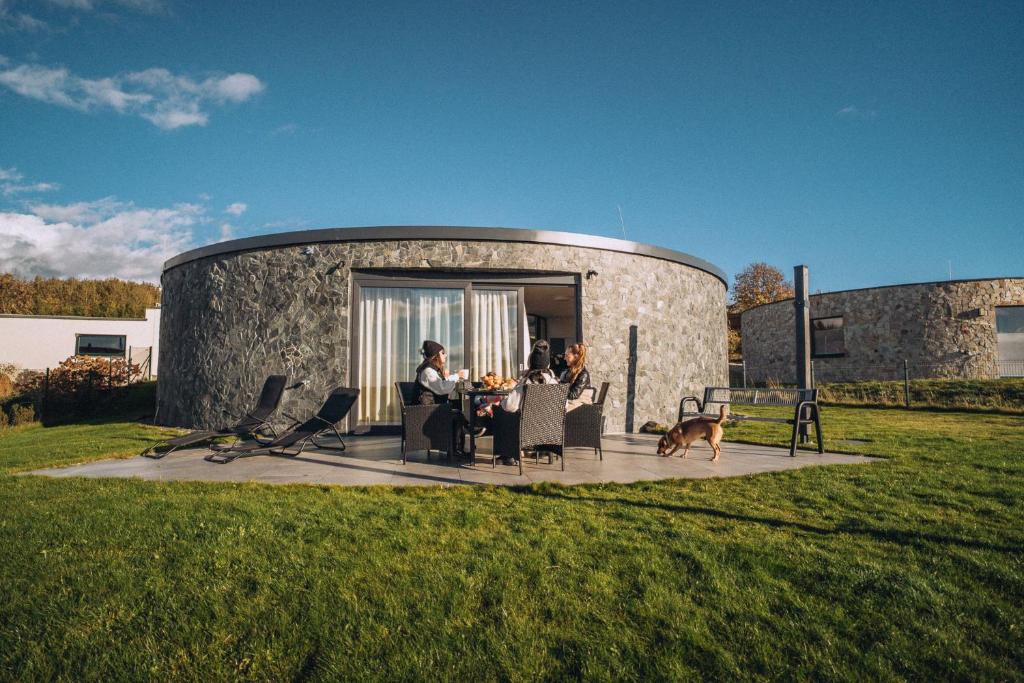 a group of people sitting at a table on a patio with a dog at Villa Kořenec in Kořenec