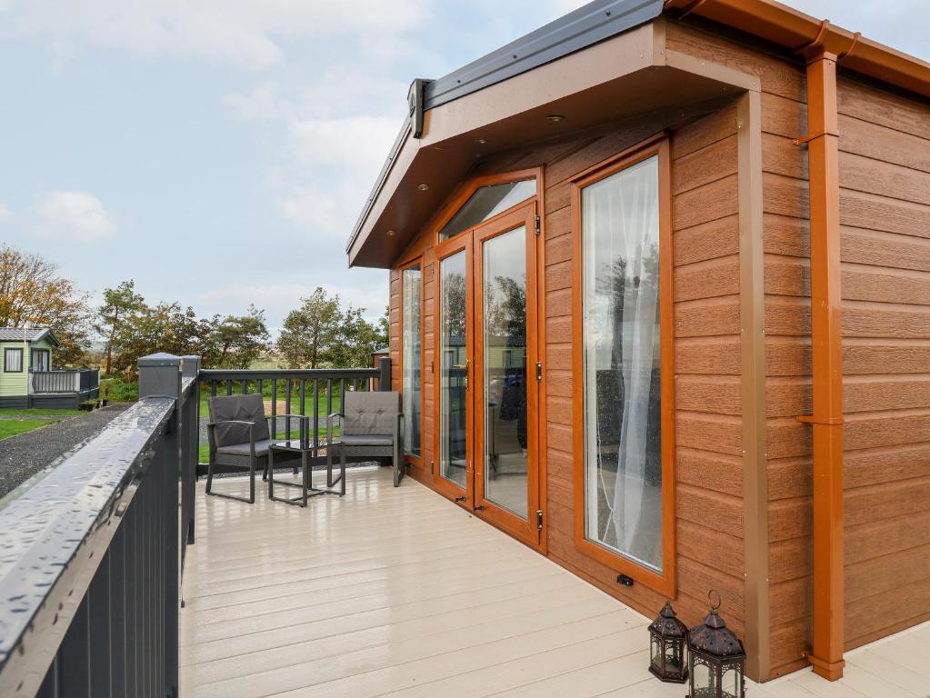 una terrazza in legno con una casa con porte in vetro di Tortworth Lodge a Ganton