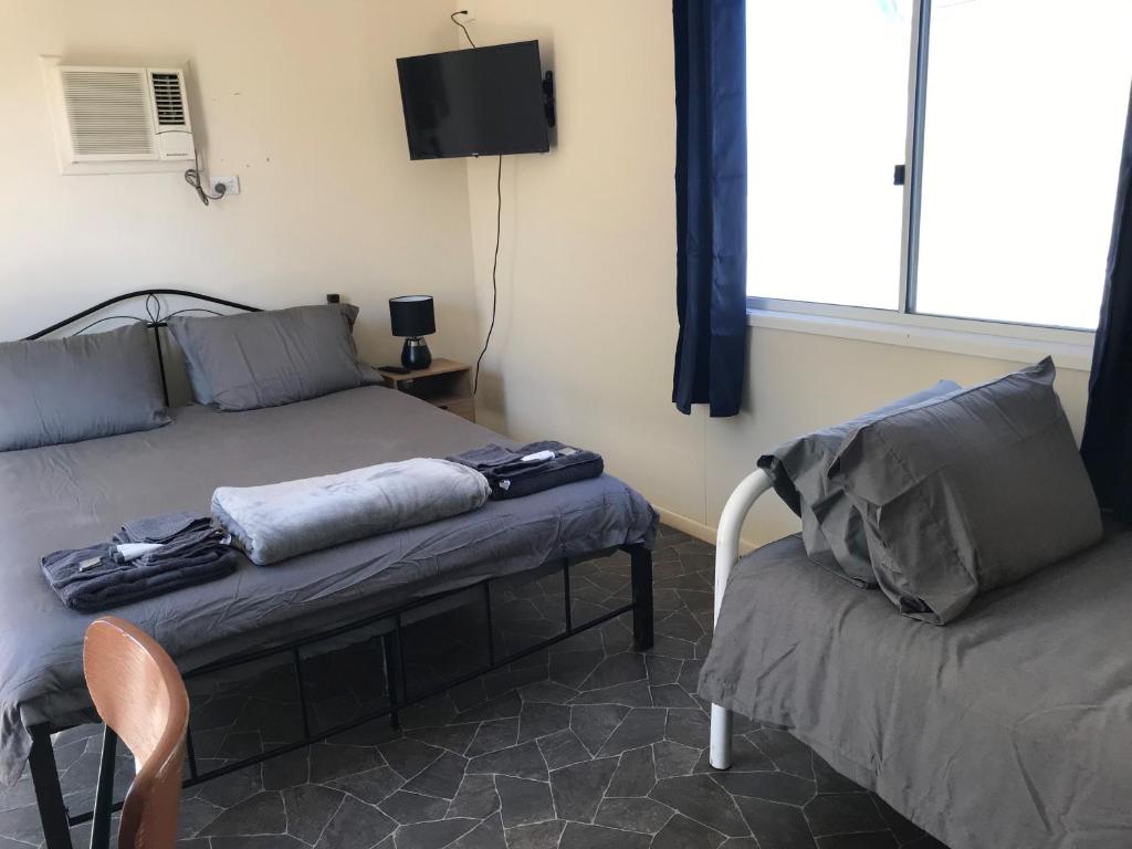een kamer met 2 bedden, een stoel en een tv bij Australian Hotel Winton Cabins in Winton