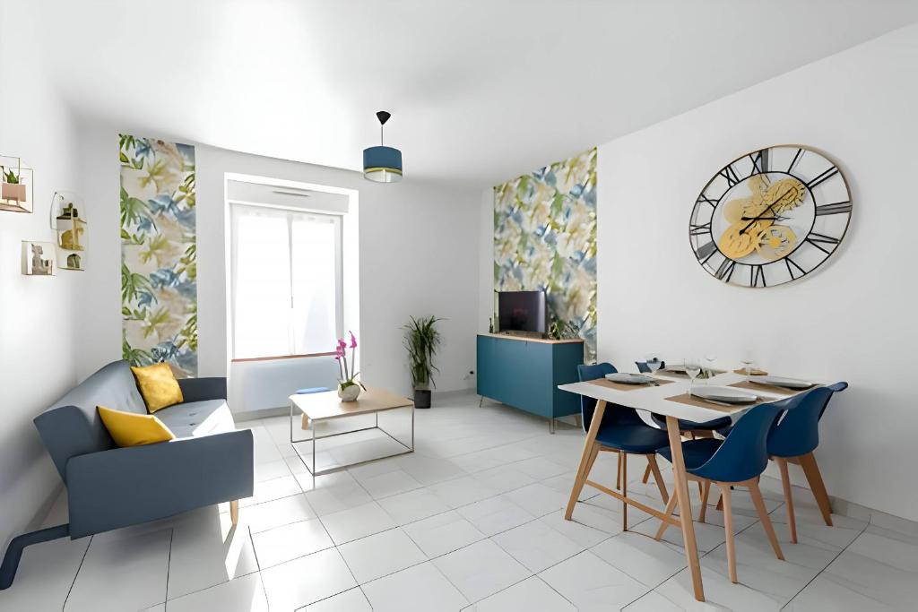 - un salon avec une table et une horloge murale dans l'établissement Le Camélia - Parking - 5pers - Rêve Au Mans, au Mans