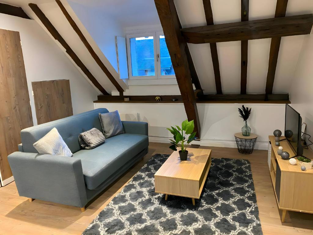 ein Wohnzimmer mit einem blauen Sofa und einem Tisch in der Unterkunft Le Contemporain - 5p - Centre Ecommoy - Rêve au Mans in Écommoy