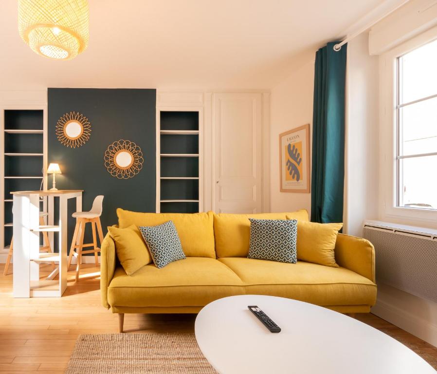 ein Wohnzimmer mit einem gelben Sofa und einem Tisch in der Unterkunft Le SweetMorning - Gare - Palais des Congrès - Rêve au Mans in Le Mans