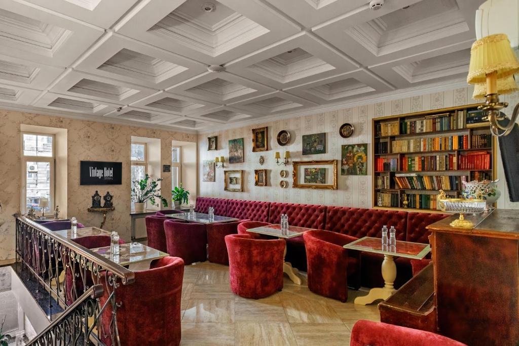un restaurante con sillas rojas, mesas y libros en Vintage Art Hotel en Odesa