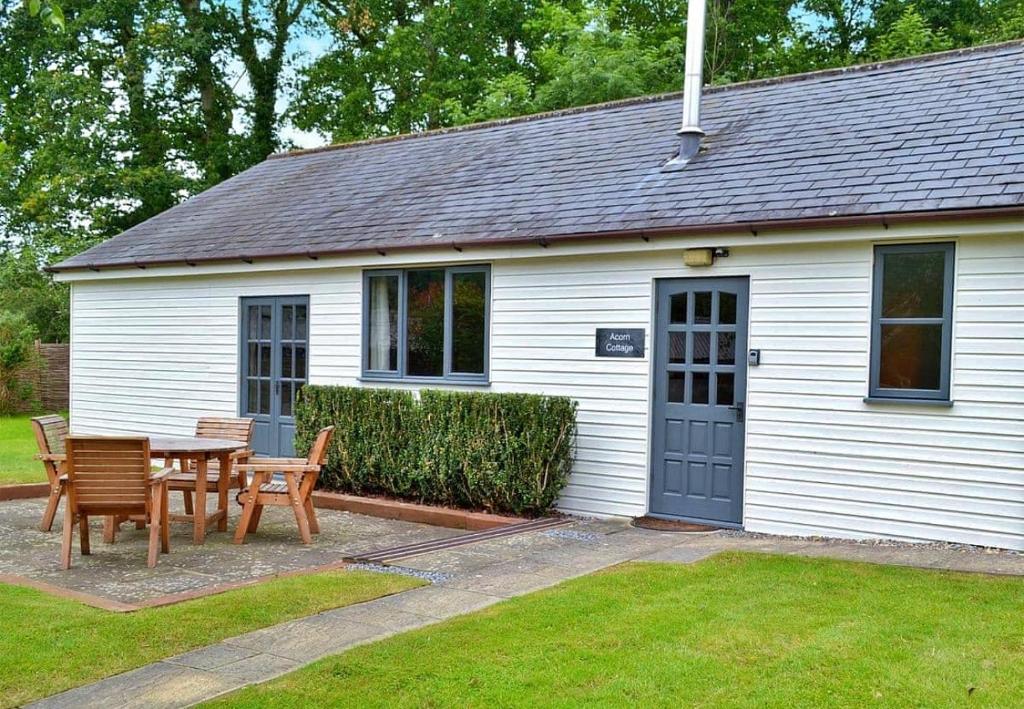 ein weißes Haus mit einem Tisch und Stühlen im Hof in der Unterkunft Finest Retreats - Little Dunley - Acorn Cottage in Bovey Tracey