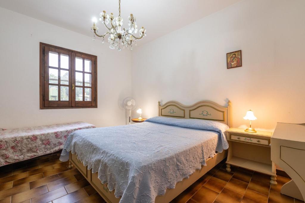Schlafzimmer mit einem Bett und einem Kronleuchter in der Unterkunft La Casa delle Rose in Solanas