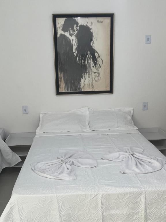 Un dormitorio con una cama blanca con una foto en la pared en POUSADA RIO PERUYPE, en Nova Viçosa