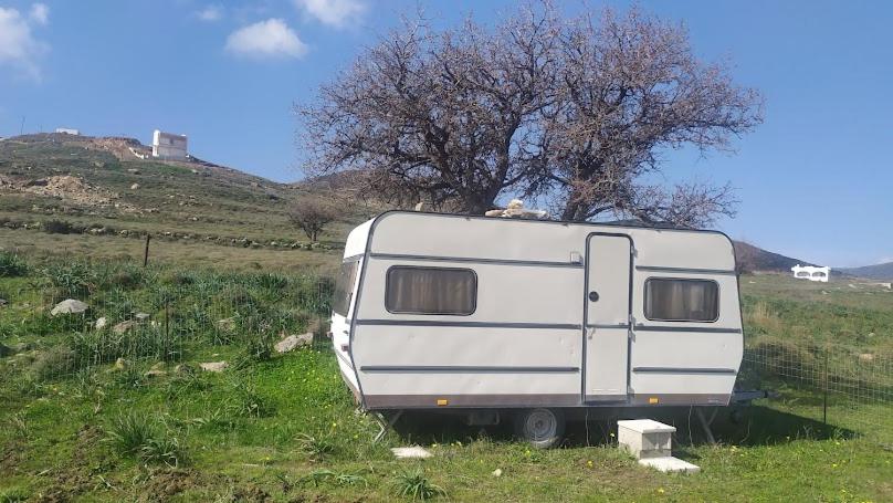 a white trailer parked in a field next to a tree at Camping.Karystos Melodia in Karistos