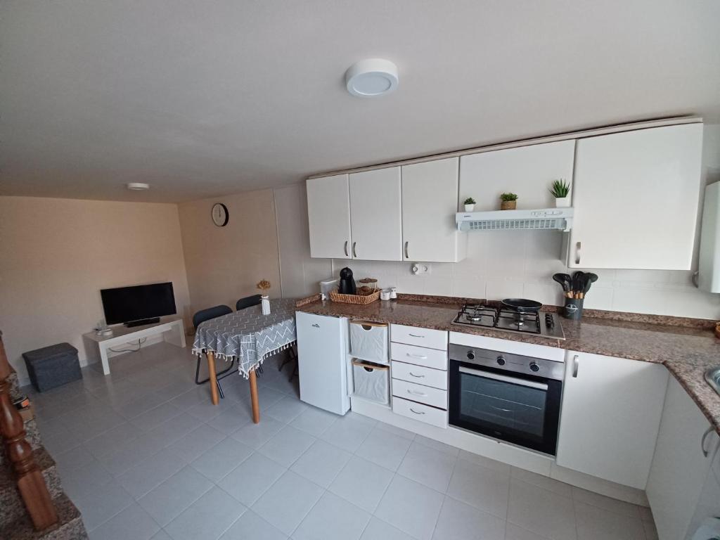 a kitchen with white cabinets and a table and a television at Casa Montecelo in Paderne