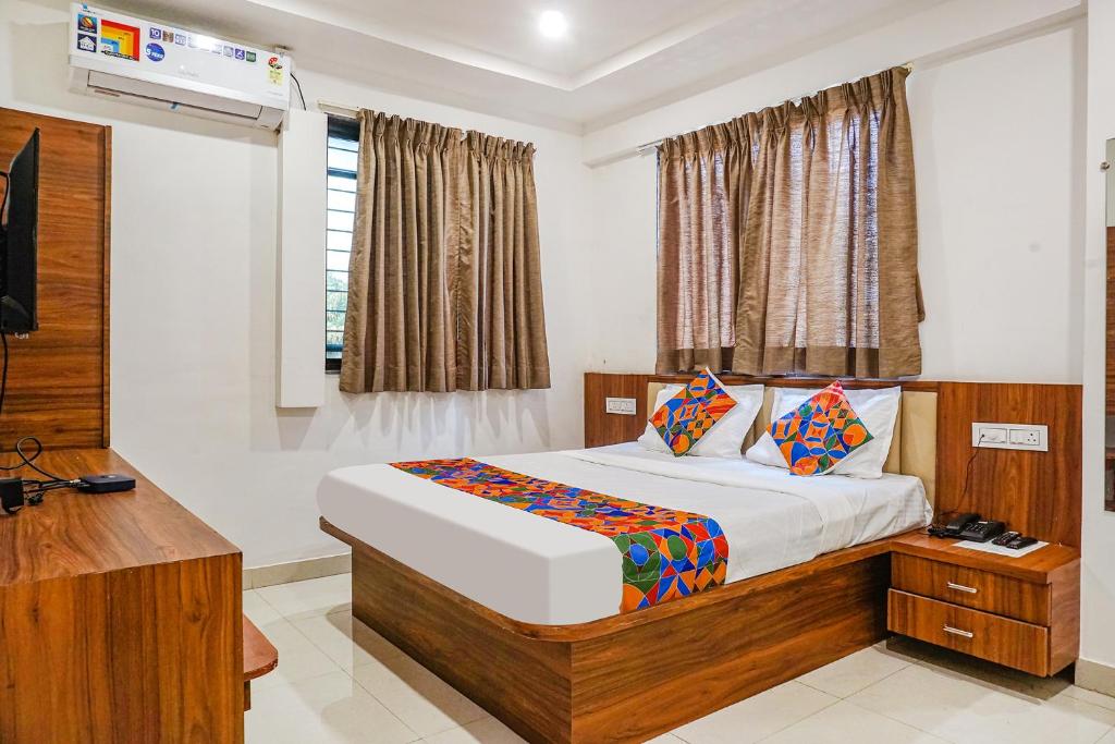 a bedroom with a bed and a desk and a window at FabExpress Sathvik Executive in Pune