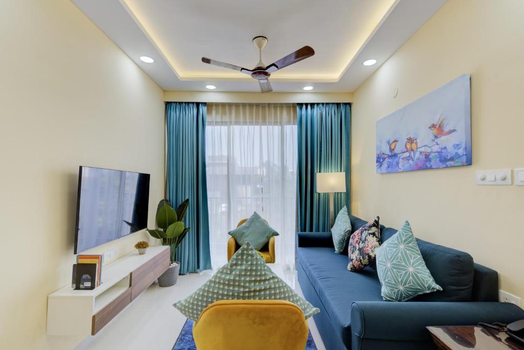 a living room with a blue couch and a tv at Luxe 2BHK by Coral BnB with Pool access in Dabolim