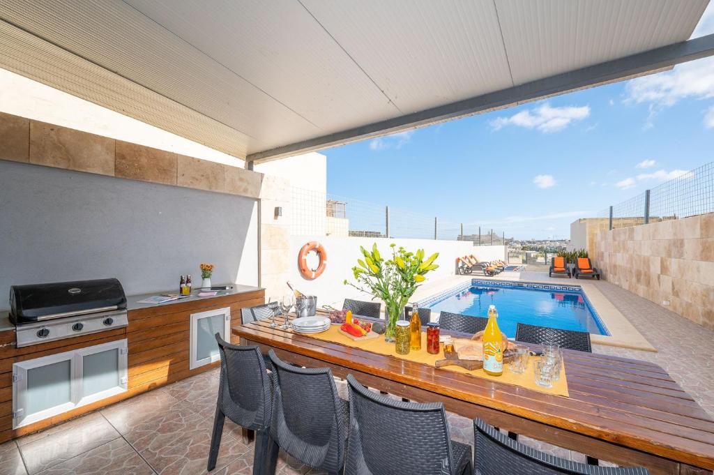 a patio with a table and chairs and a swimming pool at Ta Kalang Holiday Home in Kerċem