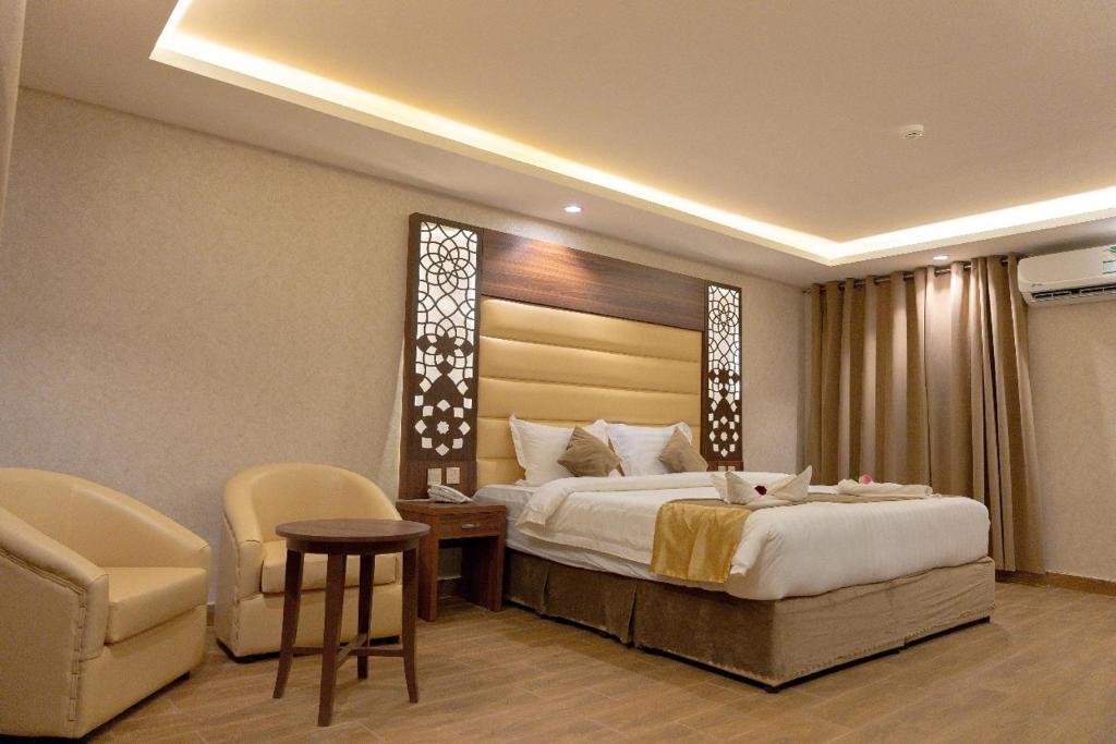 a bedroom with a bed and a table and a chair at Sahary Al Ula Resort in AlUla