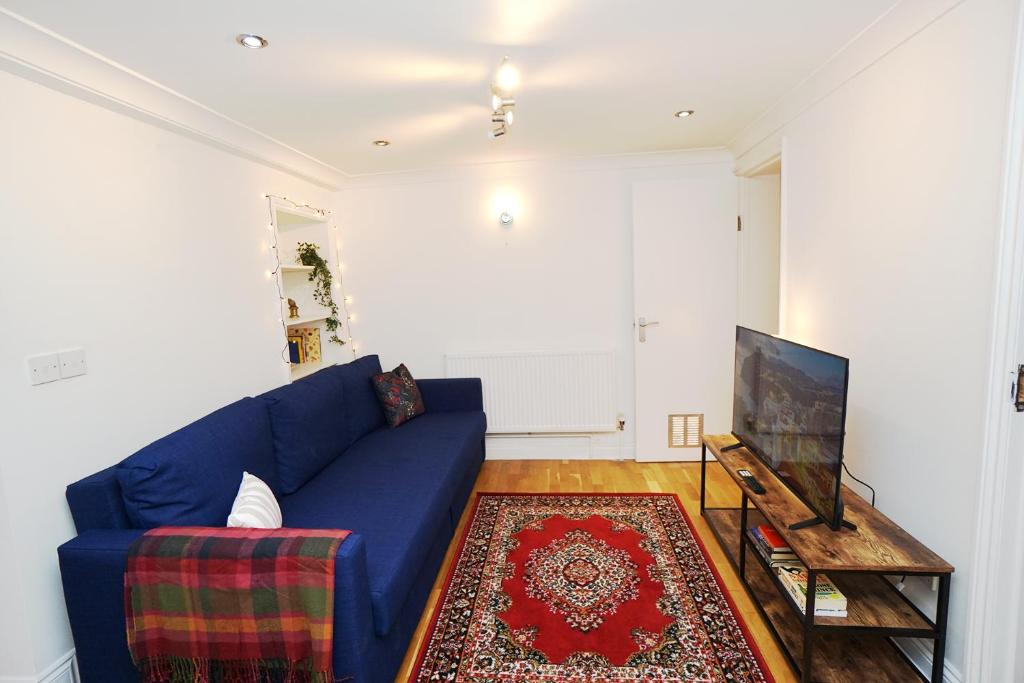 sala de estar con sofá azul y TV en Cozy Retreat By Aresti Hotels, en Londres