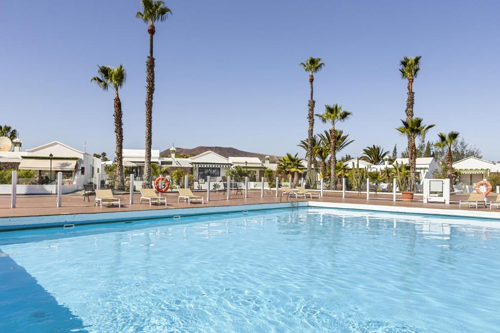 a swimming pool at a resort with palm trees at Jardin del sol 17 in Playa Blanca