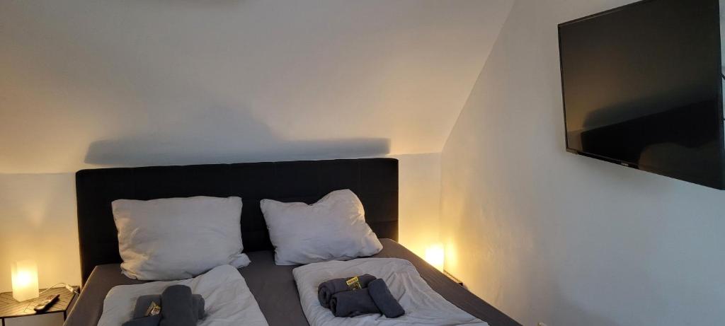 a bedroom with a bed with two pillows and a tv at Berg Messe DG 1Zi, K,D,B Parkplatz, W-Lan, Homeoffice in Bergisch Gladbach