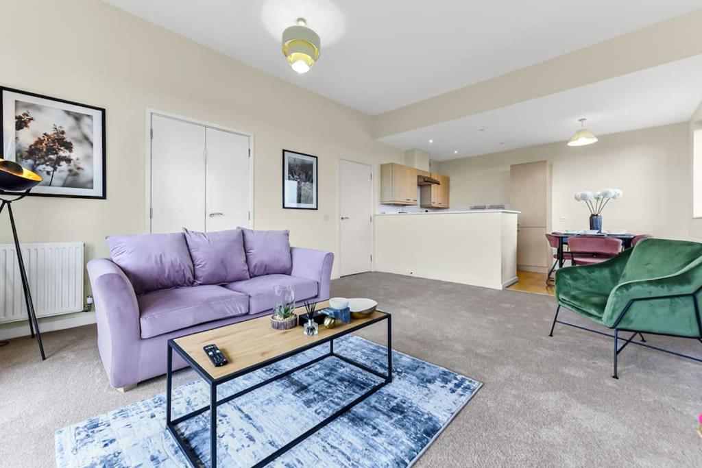 ein Wohnzimmer mit einem lila Sofa und einem Tisch in der Unterkunft City Penthouse with Scenic View Balcony in Milton Keynes