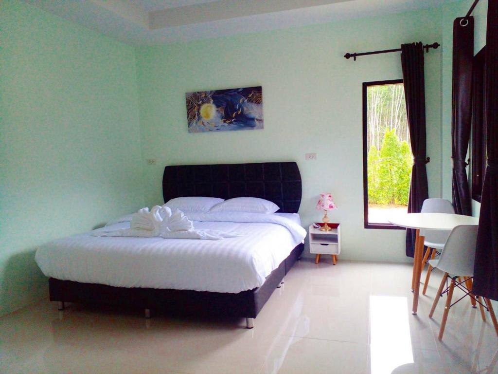 1 dormitorio con cama, mesa y ventana en การ์เด้นวิว รีสอร์ท en Trang