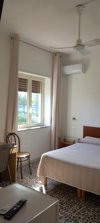 a bedroom with a bed and a desk and a window at Hotel Conca d'Oro in Stalettì