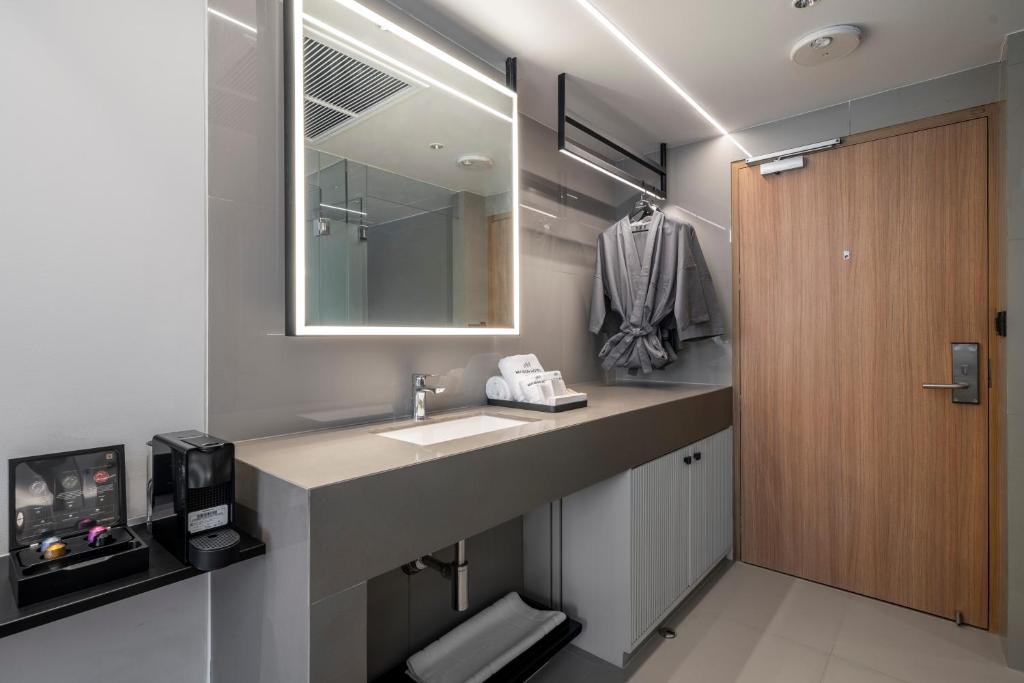 A compact vanity area with a lit mirror, coffee equipment and an open clothing rail beside the entry door.