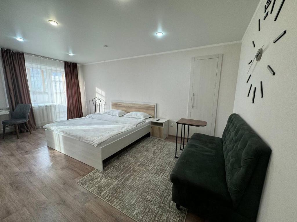 1 dormitorio con 1 cama, 1 silla y 1 mesa en Светлые и уютные апартаменты с выходом в центральный парк, en Kostanái