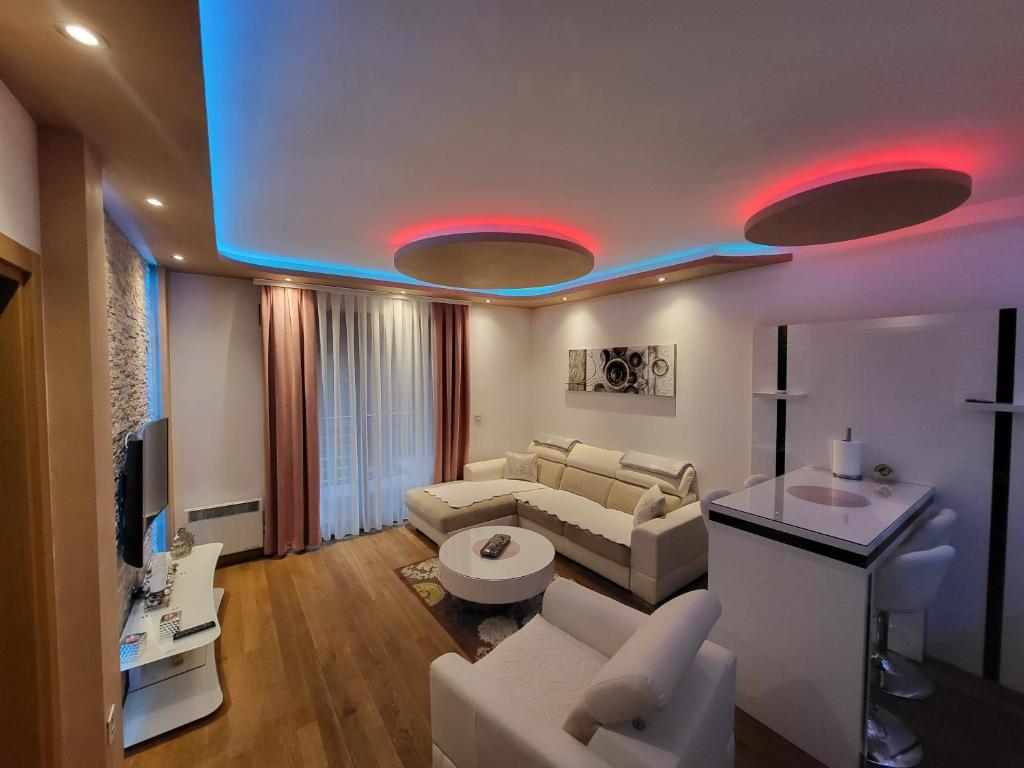 una sala de estar con muebles blancos y luces rojas en Apartment Crystal, en Zlatibor