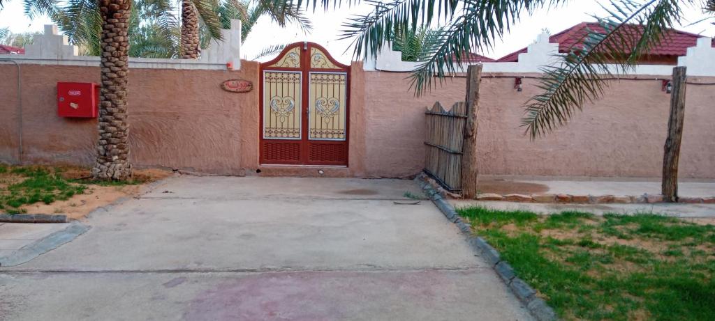 a house with a red door and a palm tree at استراحة وزنه in Buraydah