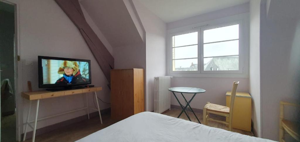 1 dormitorio con 1 cama y mesa con TV en Les Géraniums Sullylois en Sully-sur-Loire