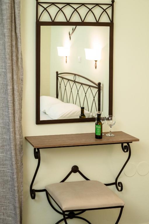 a mirror on a wall with a shelf and a chair at Konstantinos Hotel & Apartments 2 in Nydri